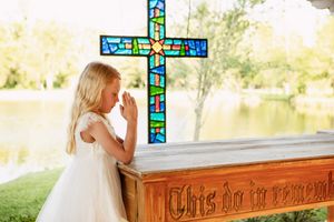 White dress against stained glass cross in church setting.