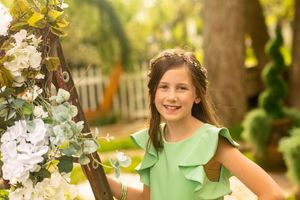 Portrait in a garden setting with white flowers and mint green ruffled dress.