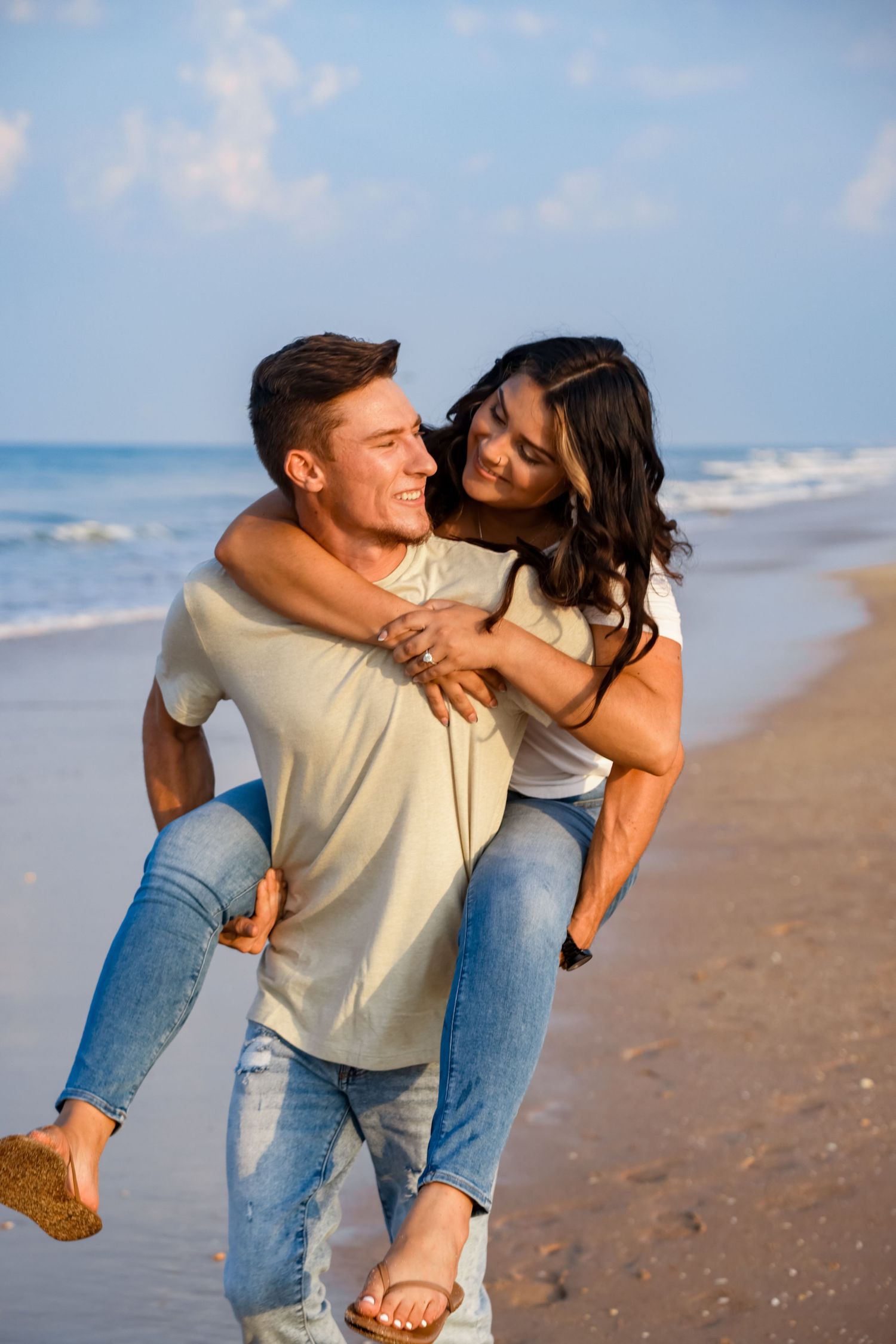 A playful piggyback ride along the beach at sunset with waves in the background.