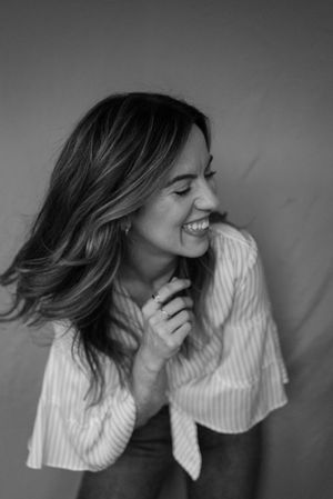 Black and white portrait capturing genuine laughter and casual pose.