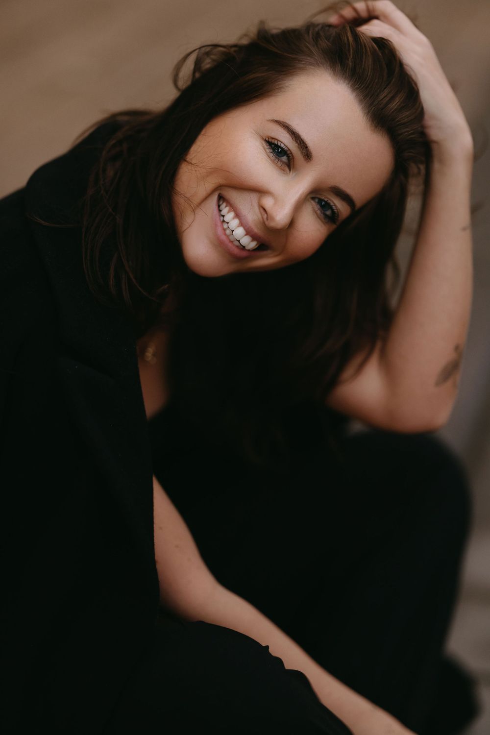 Warm toned portrait showing joyful expression and dark hair against neutral background.