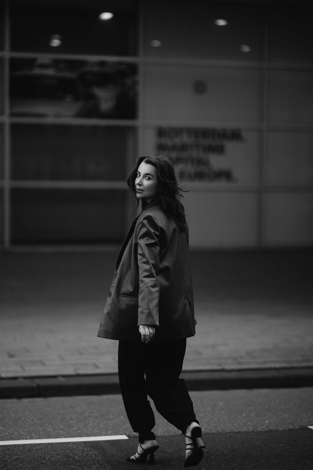 Monochromatic urban fashion portrait featuring a relaxed oversized coat and casual streetwear ensemble.
