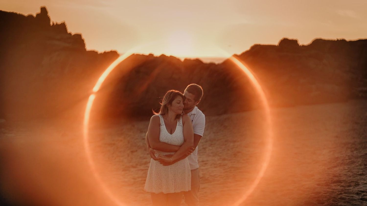 A silhouetted couple against a stunning solar eclipse creating a perfect ring of light in the desert.