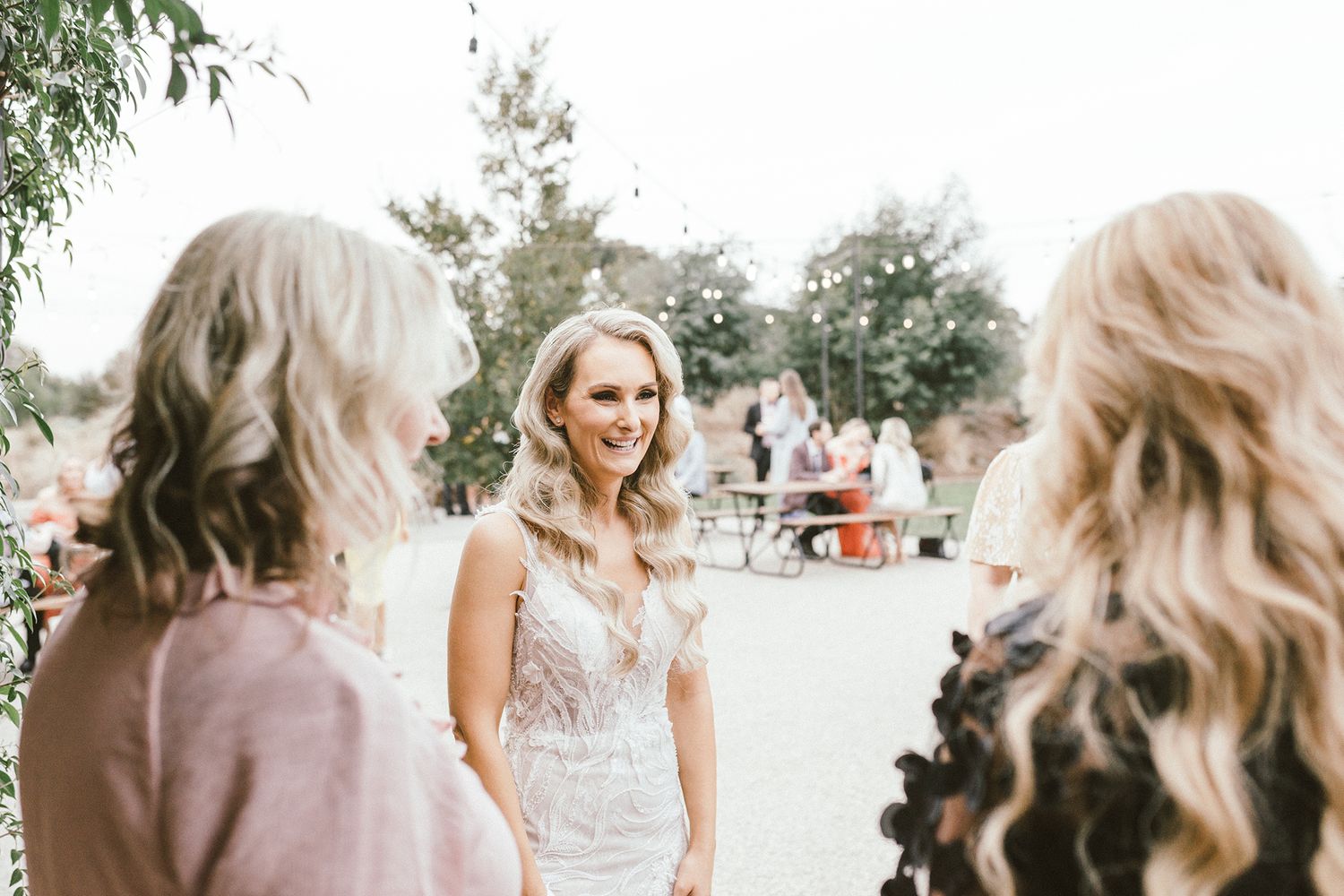 Elegant outdoor wedding celebration with guests mingling in garden setting.
