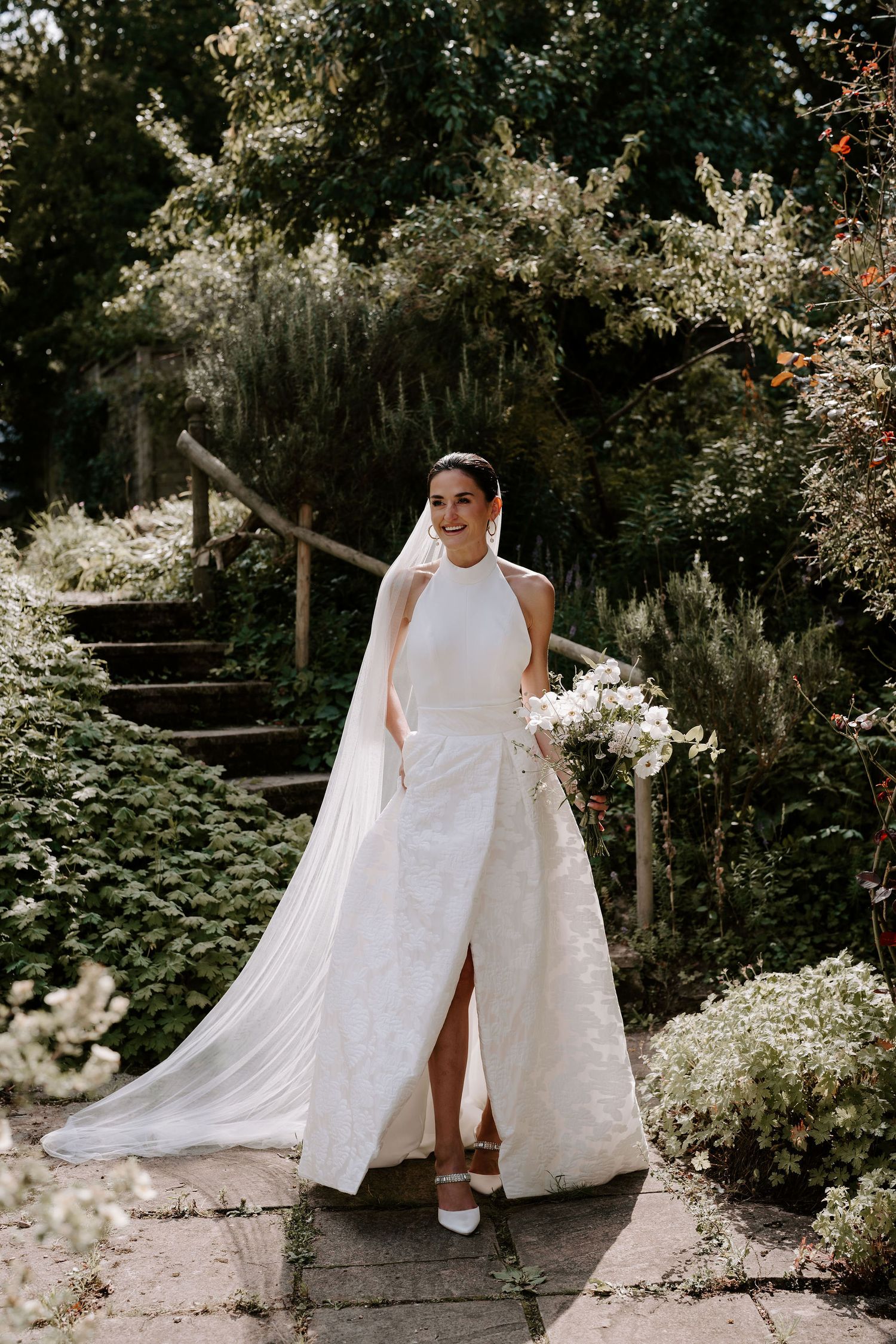 Bride stood in gardens smiling before her wedding ceremony in Oxfordshire