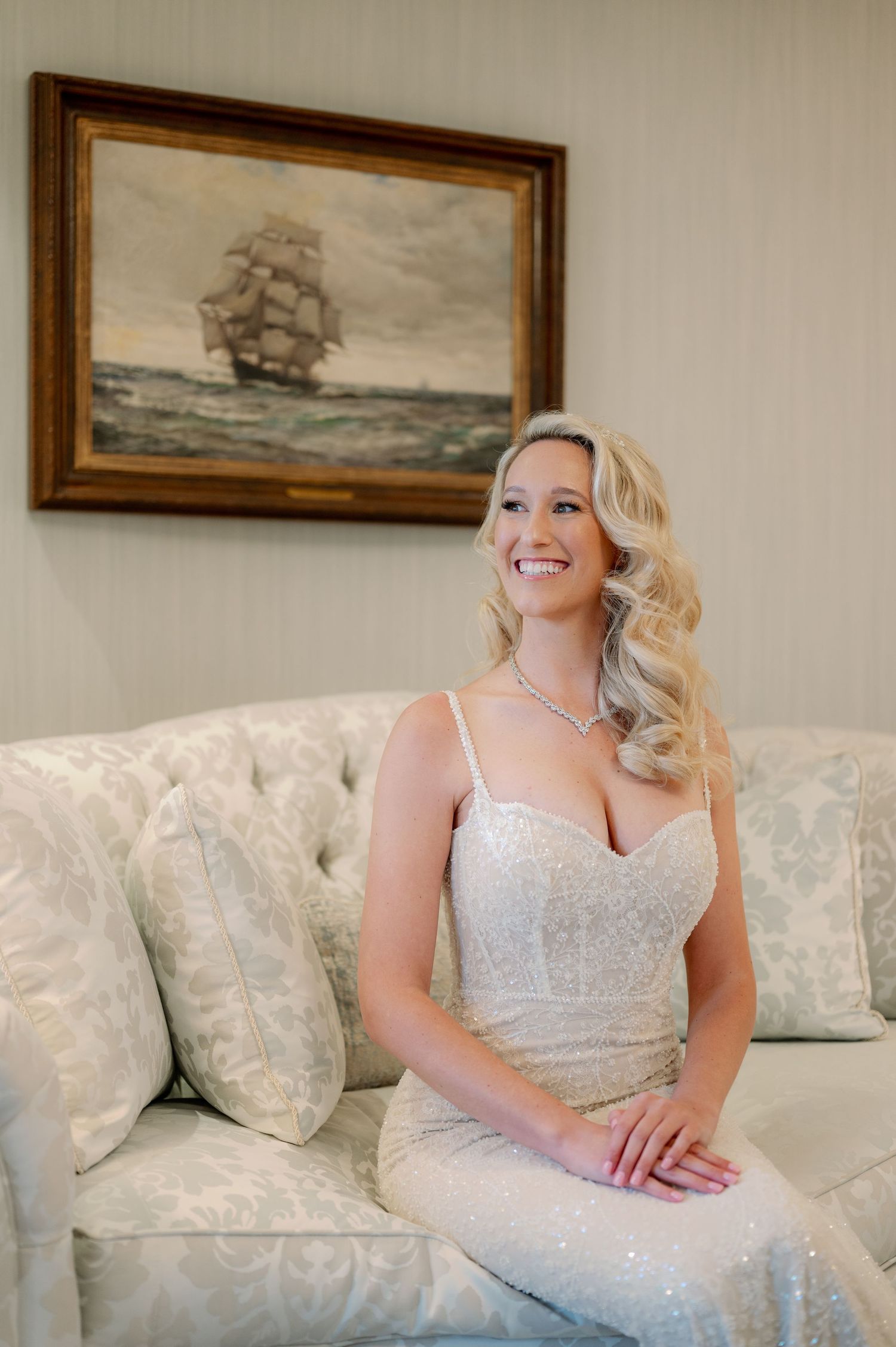 Elegant interior featuring nautical artwork and tufted sofa in soft neutral tones.