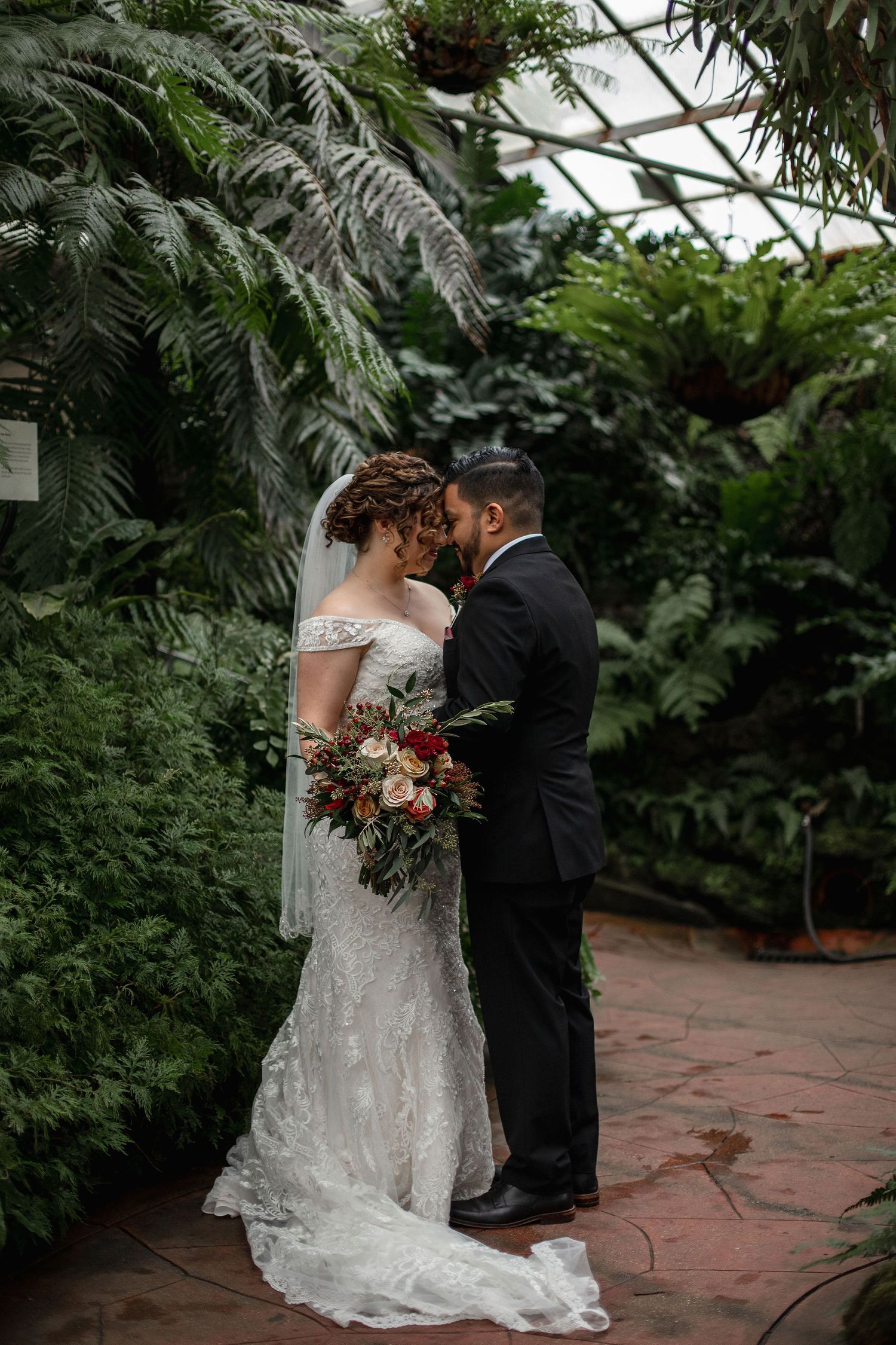 An intimate wedding moment shared between a couple surrounded by tropical plants.