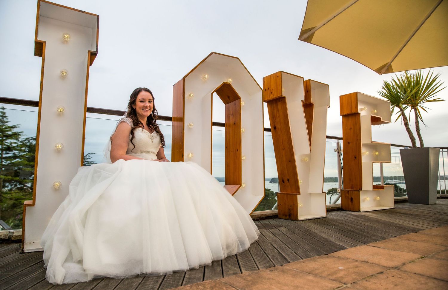 A white wedding dress against large decorative LOVE letters on an outdoor terrace.