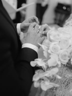 a black and white image of groom and bride exchanging rings
