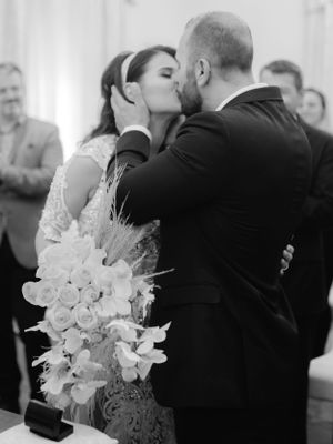 bride and groom just married and kissing in black and white image