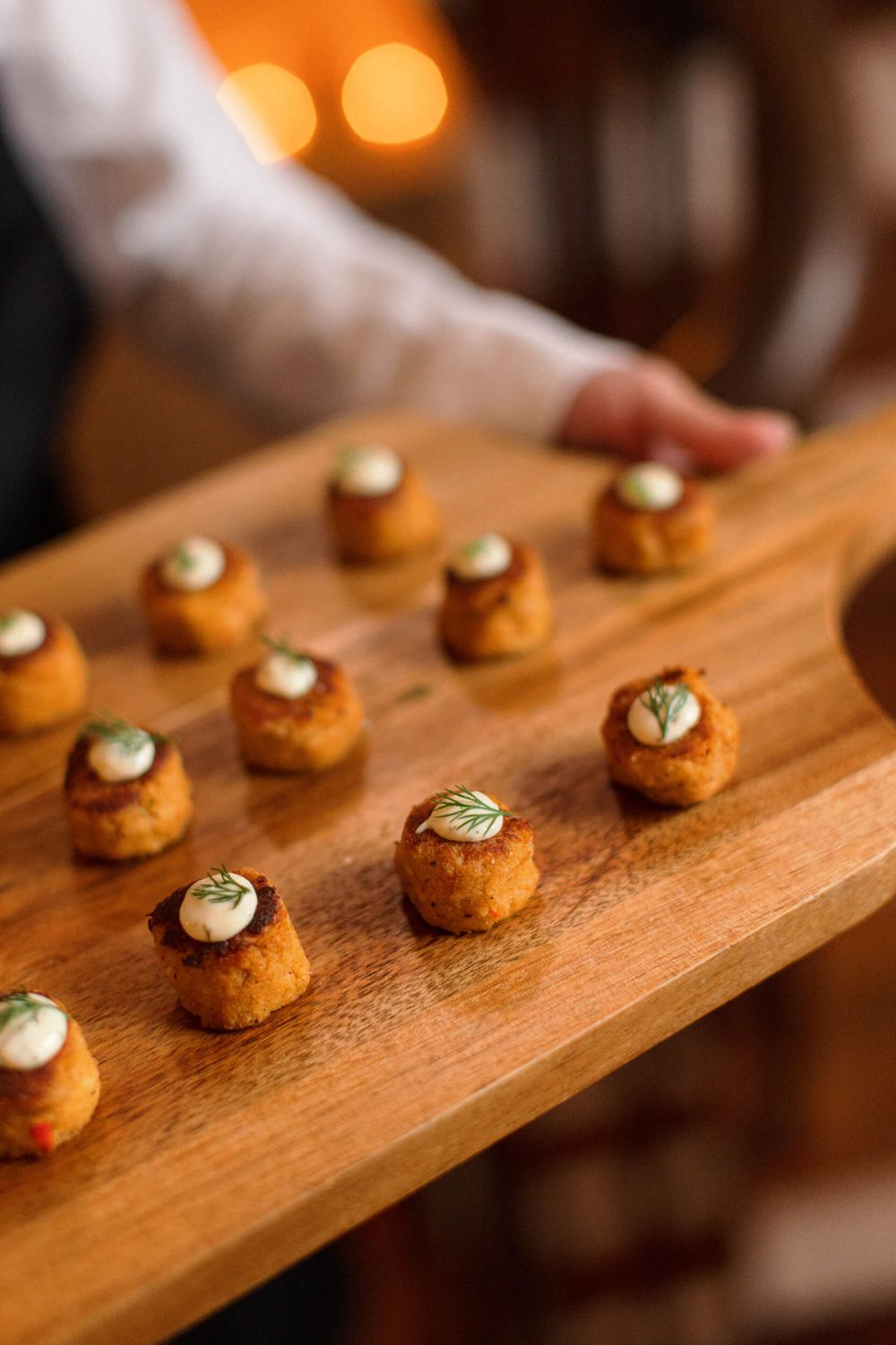 Elegant catering display of miniature appetizers garnished with herbs on a wooden serving board.