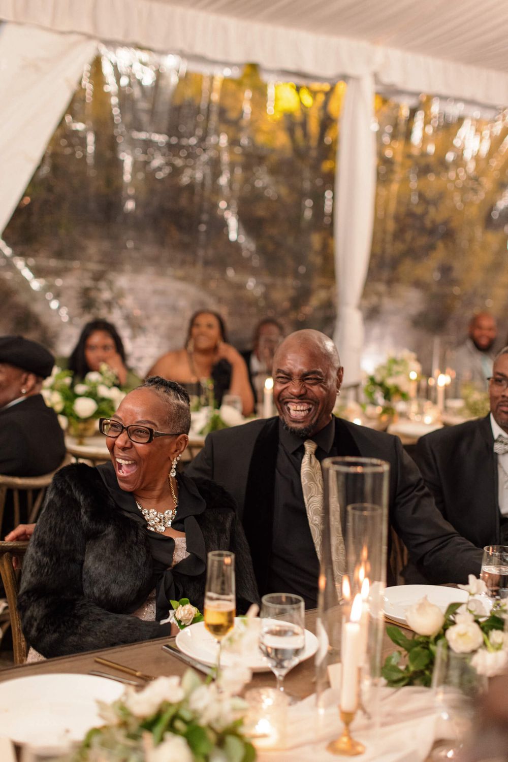 Wedding reception guests enjoy dinner at an elegantly decorated table with floral centerpieces.