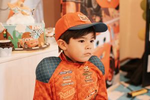 Child in orange racing costume at themed birthday celebration.