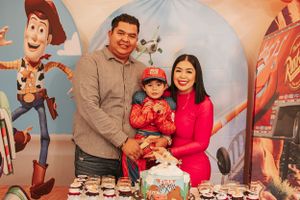A family photo at a Toy Story themed party with colorful decorations and treats on display.