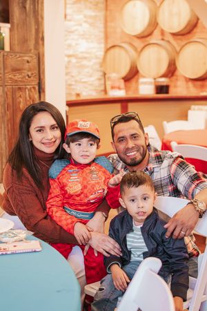 A casual family gathering with wooden barrel decor in the background.