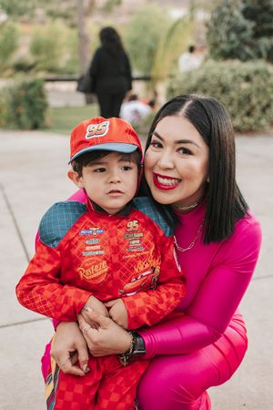 A festive outdoor portrait featuring bright fuchsia and red outfits against a natural background.
