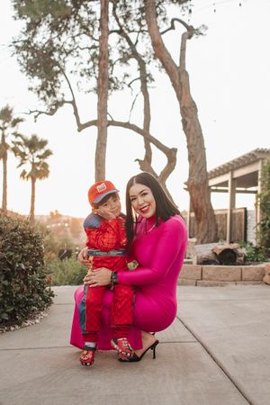 A joyful outdoor portrait showing matching vibrant pink and red outfits during golden hour.