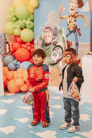 Children standing in front of Toy Story balloon decorations and character cutouts.