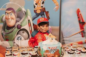 Cars-themed birthday party setup with cake and cupcakes in front of Toy Story backdrop.
