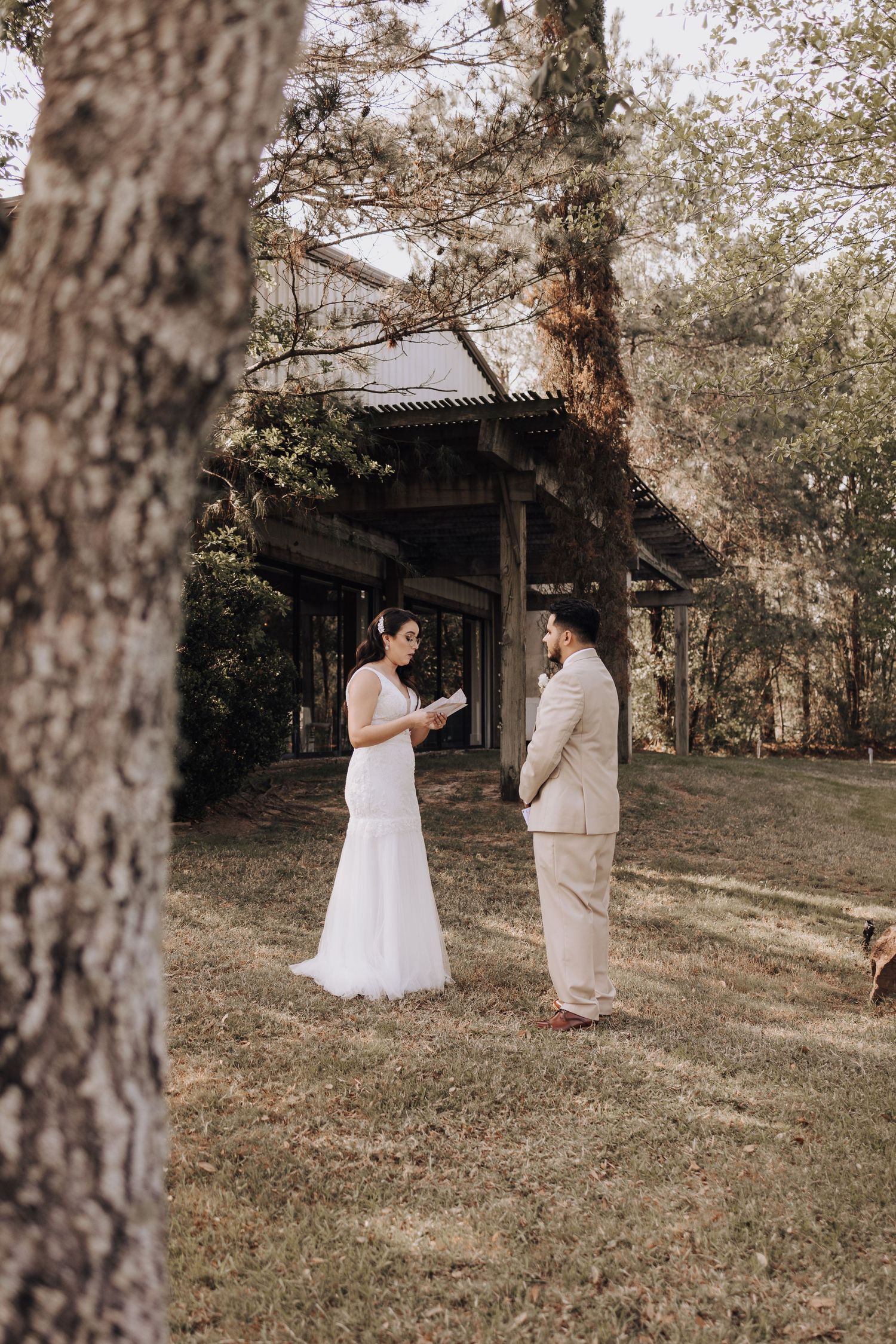 Intimate wedding ceremony taking place in front of rustic wooden structure among trees.
