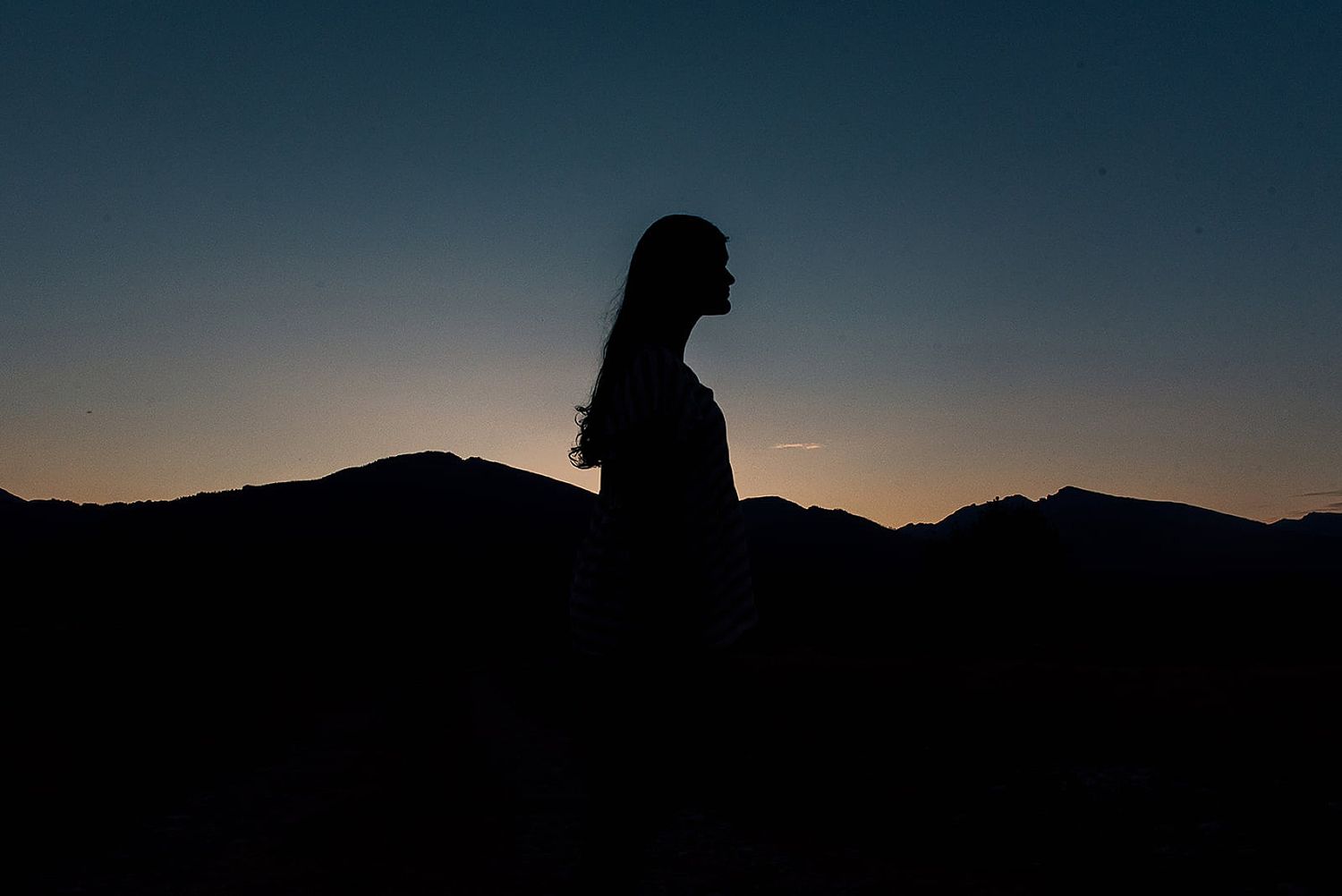 Silhouette against mountain landscape during sunset creates dramatic outdoor scene.