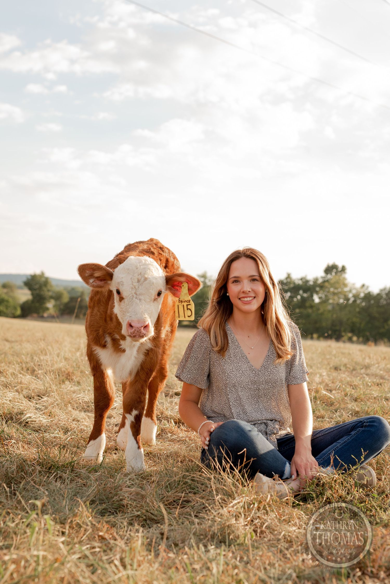 Casual outdoor portrait with friendly brown and white calf in rural pasture setting.