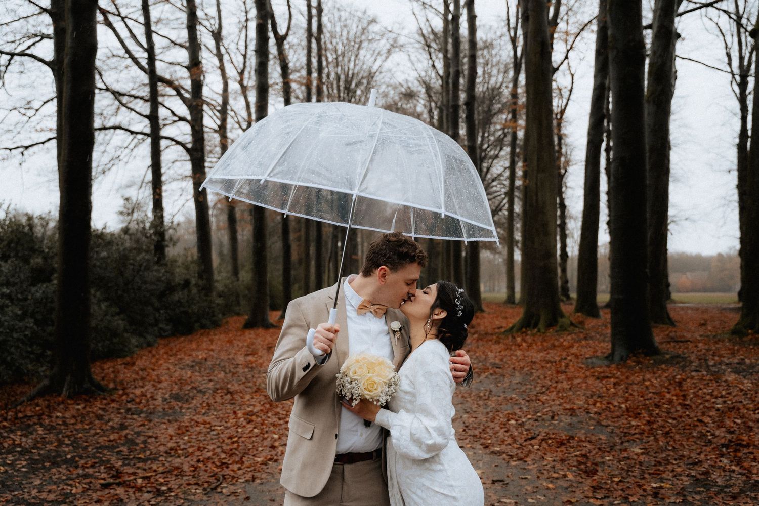 A wedding couple kissing in the rain