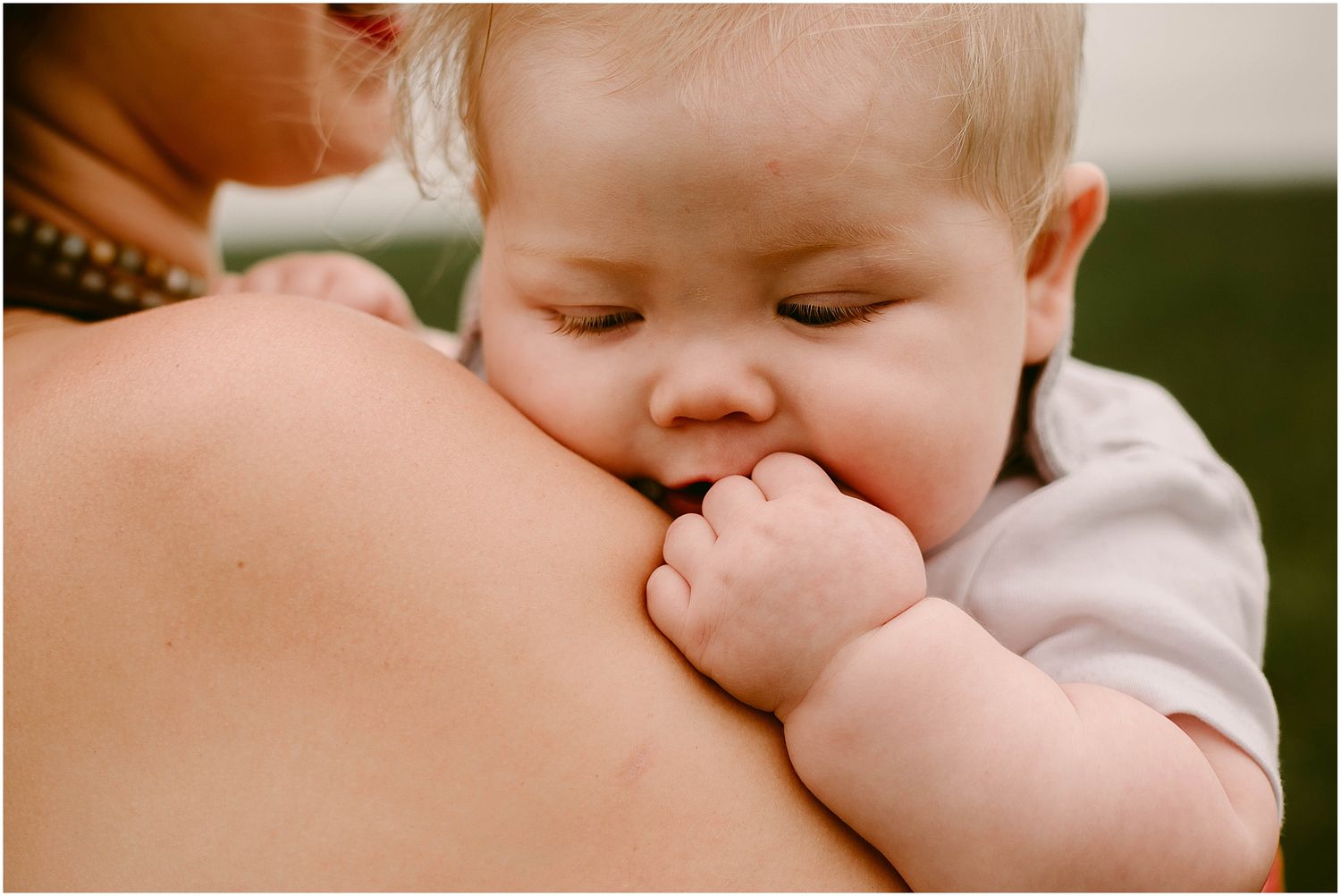 Close-up of a sleeping baby resting against someone's shoulder.