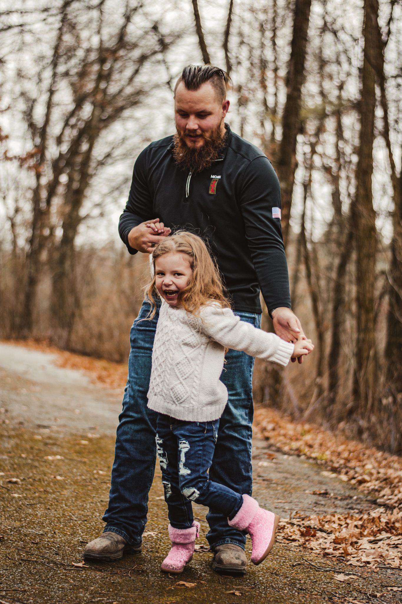 Dancing together on a woodland path surrounded by autumn trees and fallen leaves.