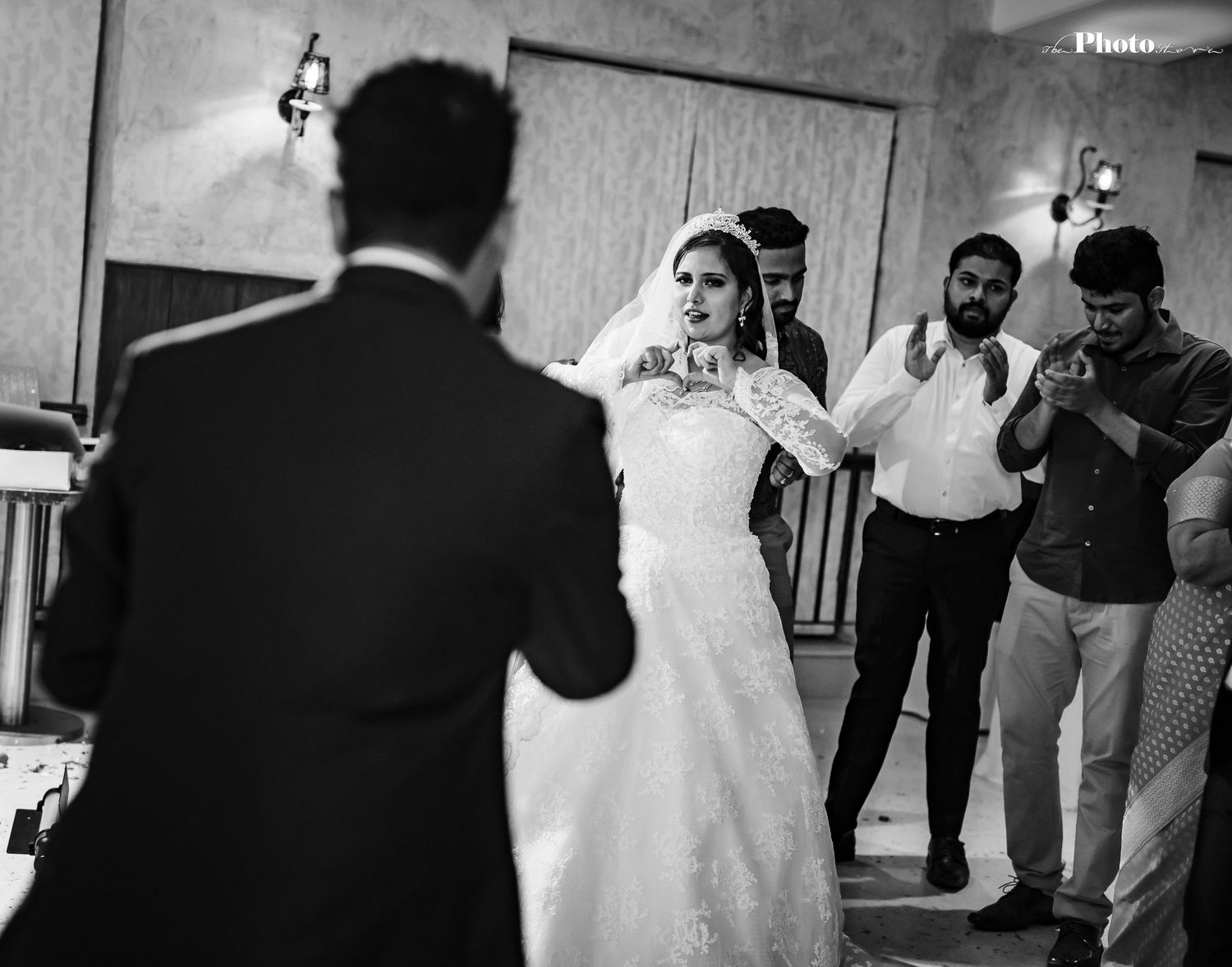Black and white wedding photo showing bride in elegant dress during reception.