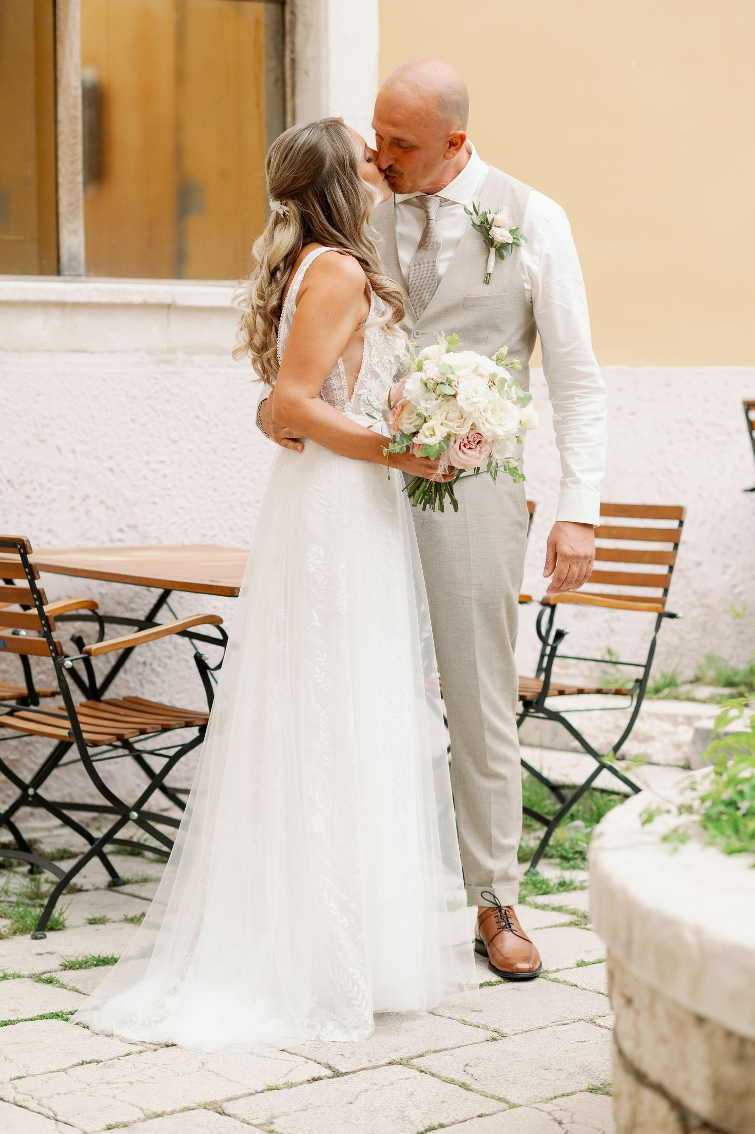 Newlyweds share intimate moment in outdoor courtyard setting.