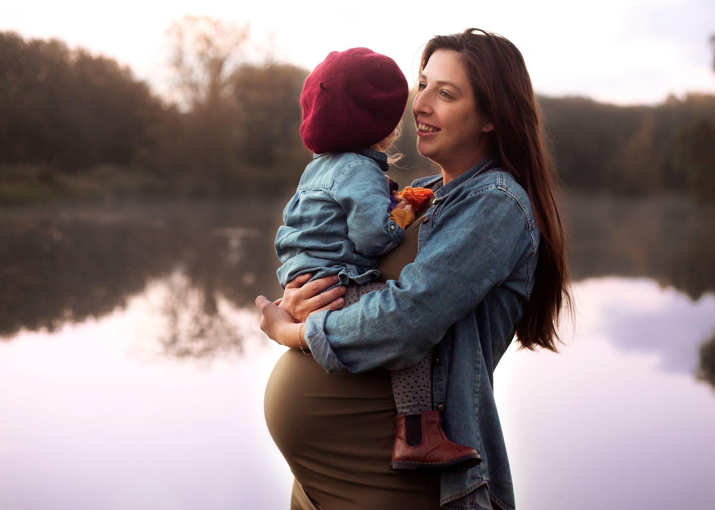 Maternity photo of mother cuddling her toddler infront of a beautiful lake in Bridport Dorset at sunrise