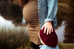 Closeup maternity photography of an expectant mother's bump in front of a lake