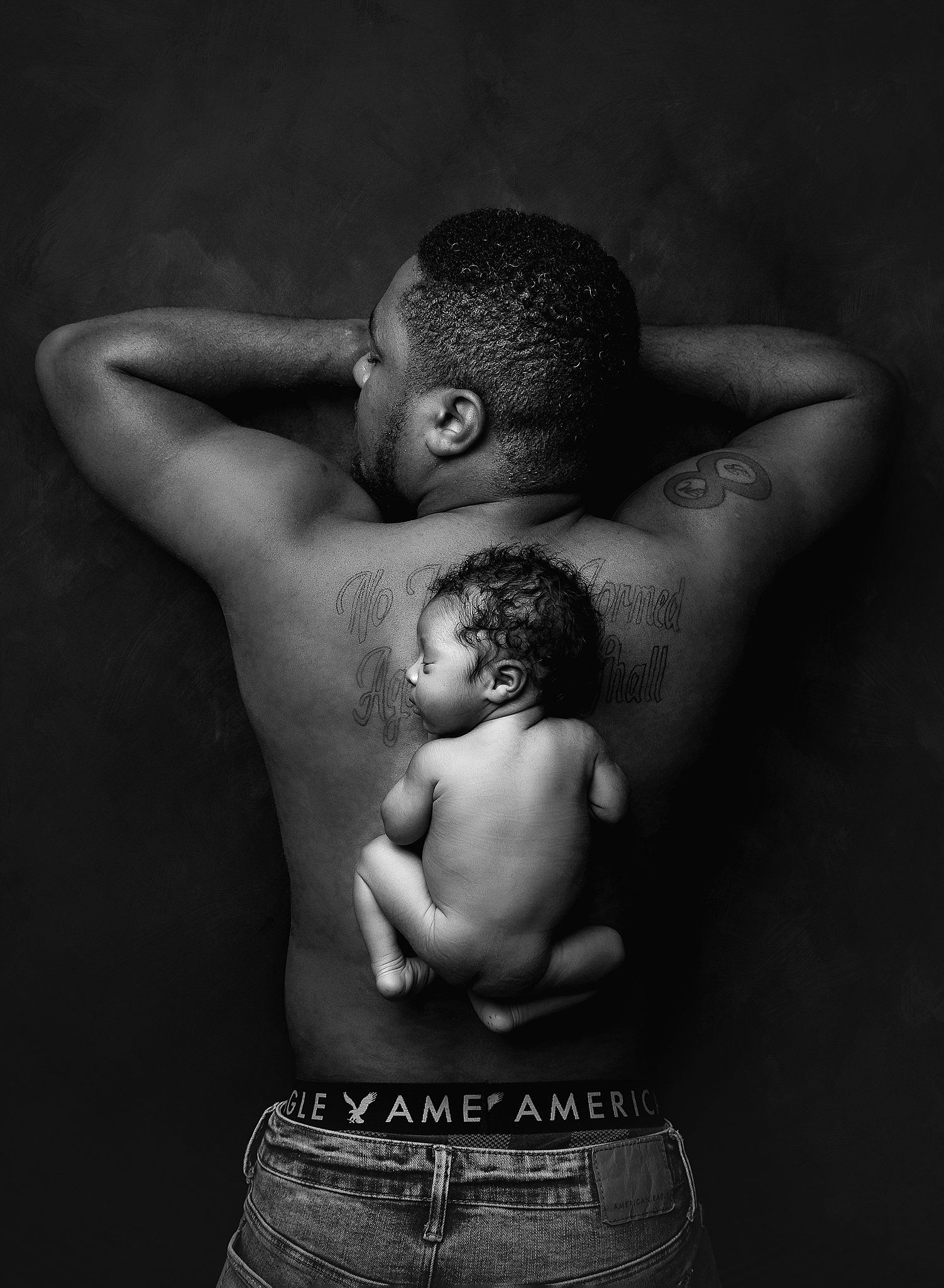 black and white newborn photo featuring dad and baby.  baby is posed on dad's back.  by valerie kay phogotgraphy