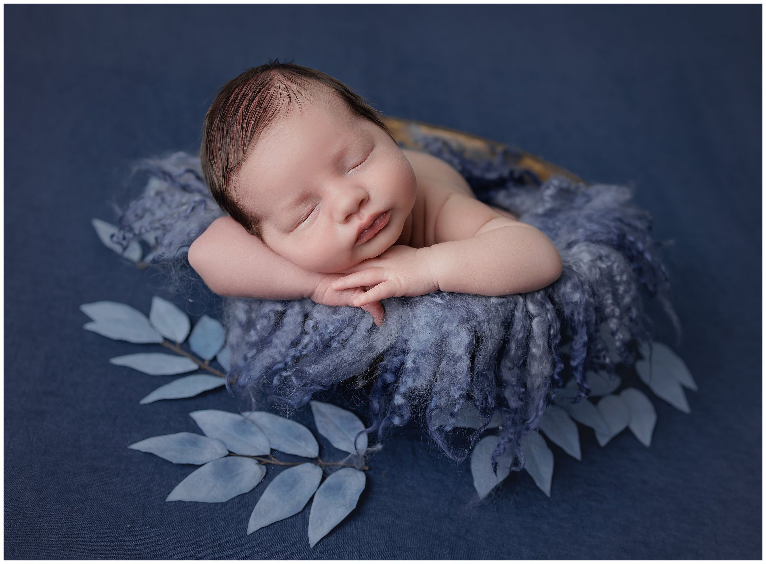 baby boy on tummy newborn session posed in bowl on blue with blue leaves. by valerie kay photography austin newborns