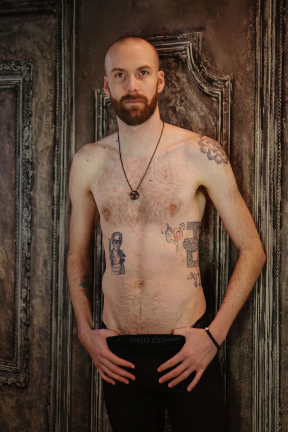 Artistic portrait against ornate wall panels showing tattoo artwork.