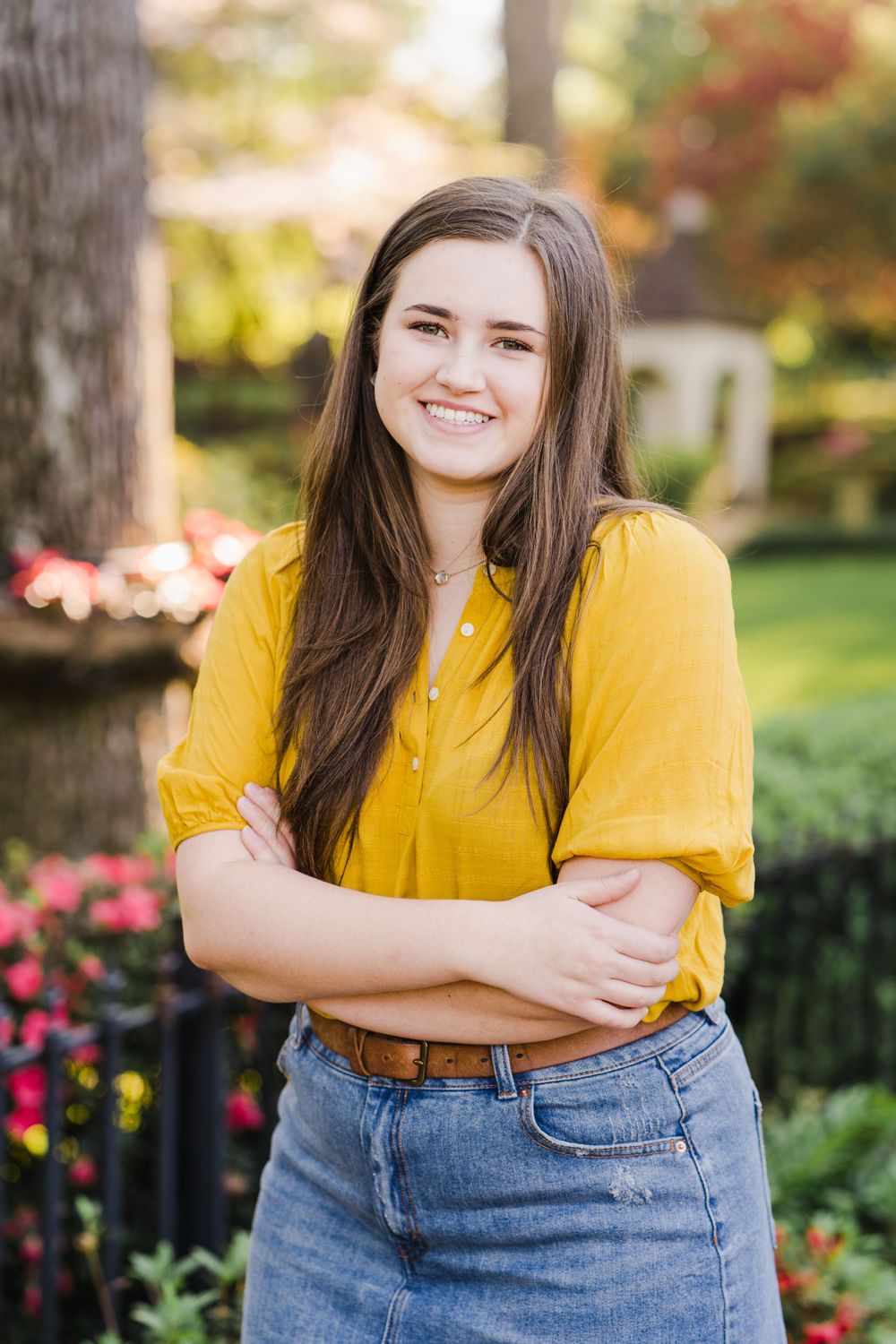 Casual spring outfit featuring yellow top and denim skirt in garden setting.