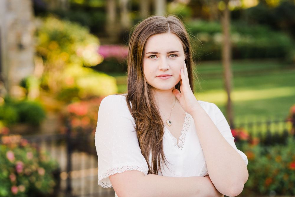 Portrait in white dress against blurred garden background.