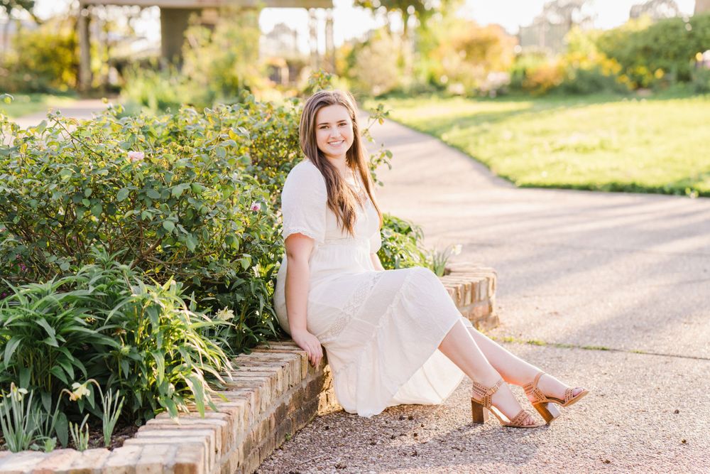 White dress outfit photographed on stone wall in garden setting.