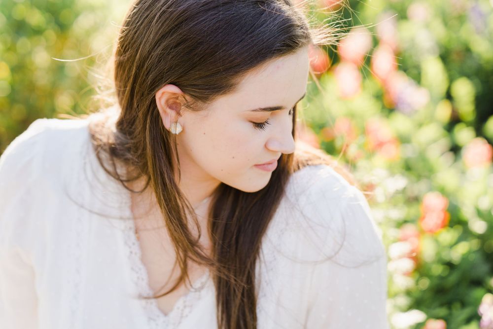 Soft focus portrait in white dress among garden flowers.