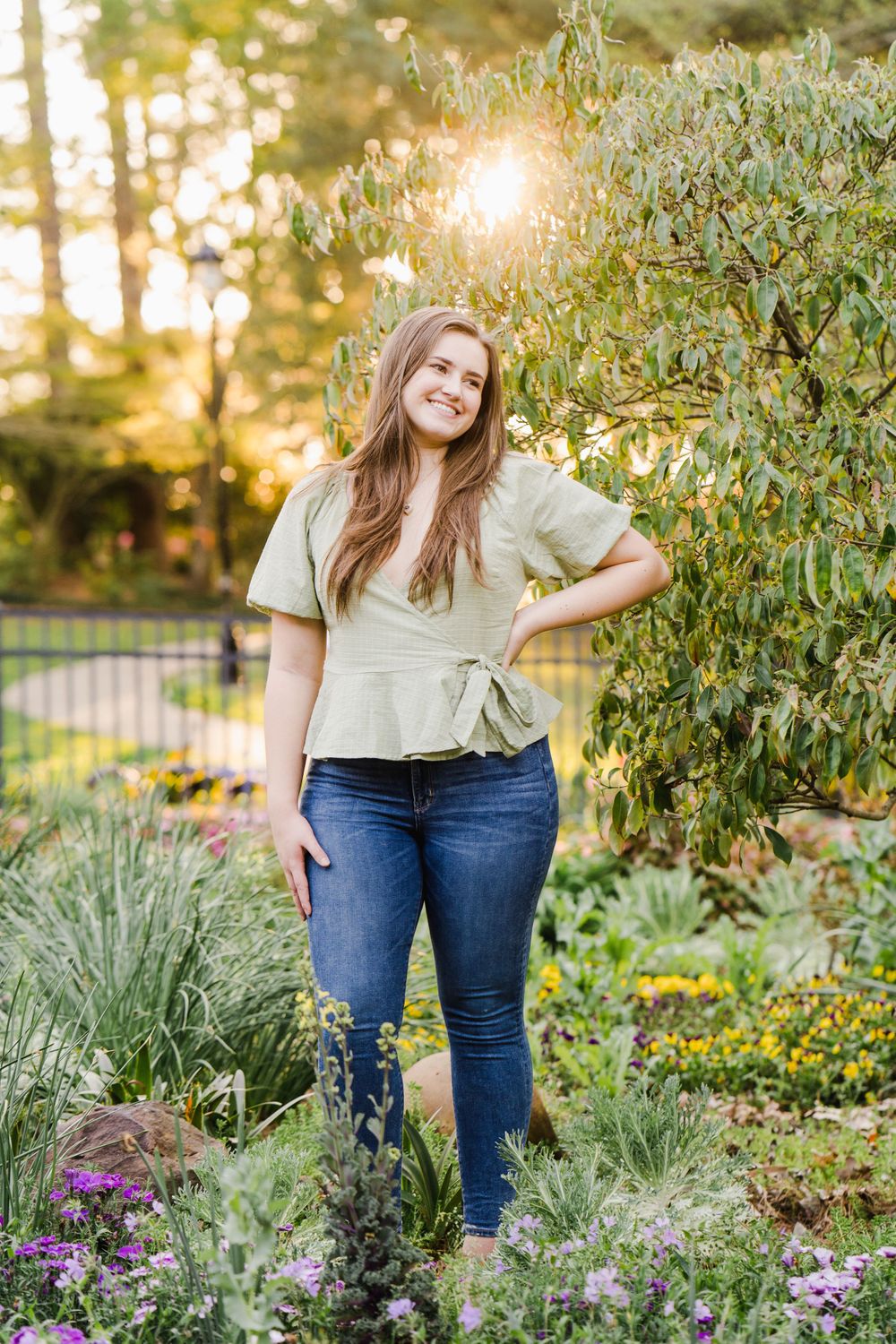 Casual outdoor portrait among blooming garden flowers at sunset.