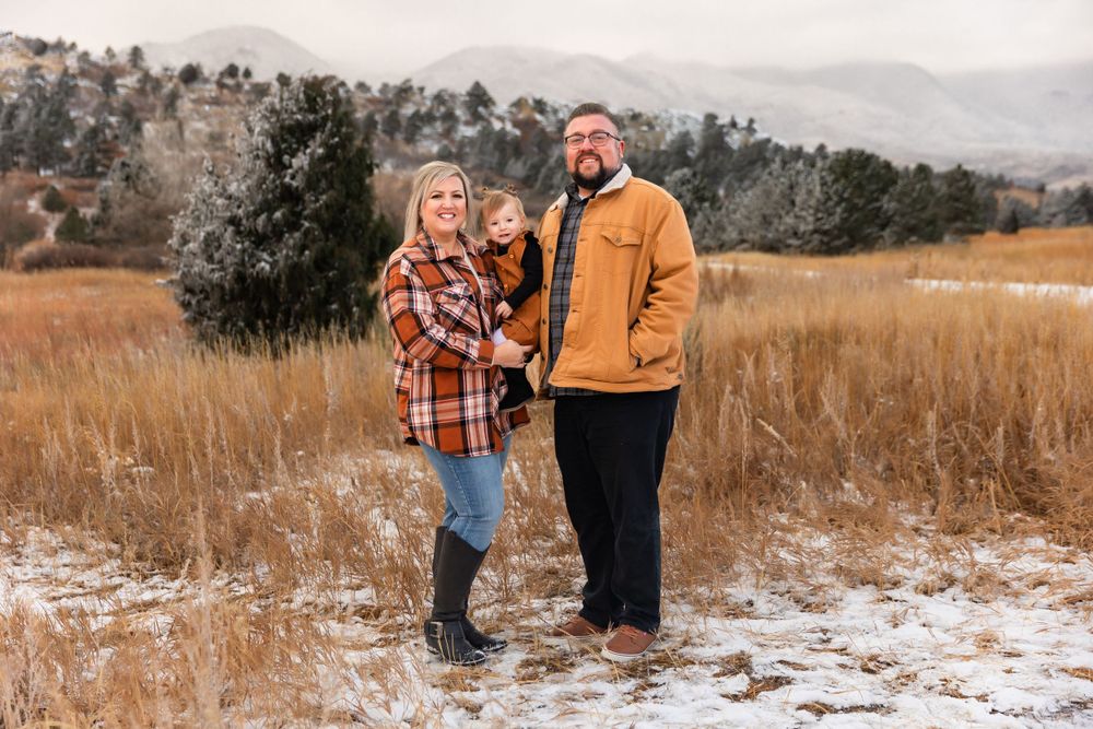 A group stands together in a snowy field with mountain foothills in the background.