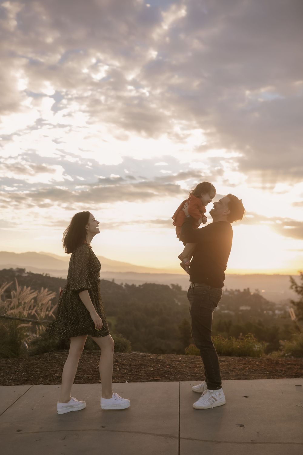 A silhouetted family scene against a dramatic sunset sky on a hilltop.