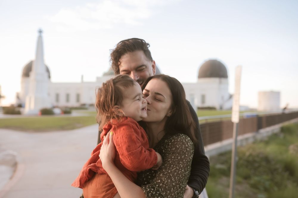 A tender family moment captured outside an observatory building at dusk.