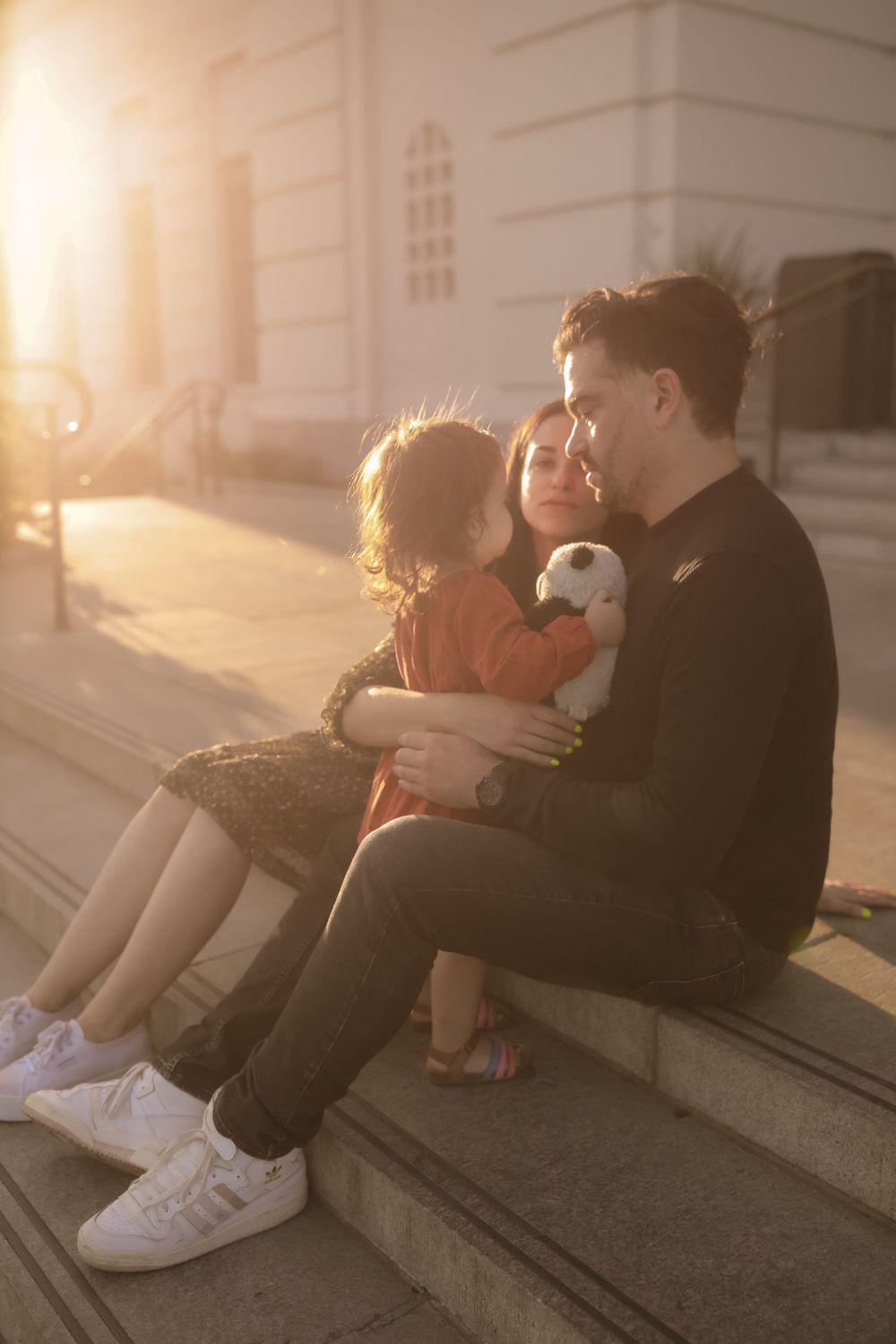 A serene family scene on steps bathed in golden sunset light.