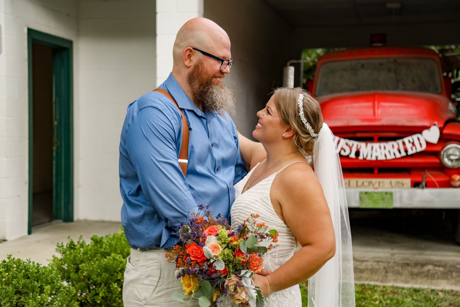 Happy couple shares a joyful moment together while holding a colorful floral bouquet.