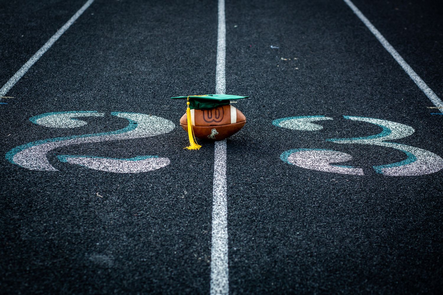 Football helmet sits on track field numbers marked in chalk.