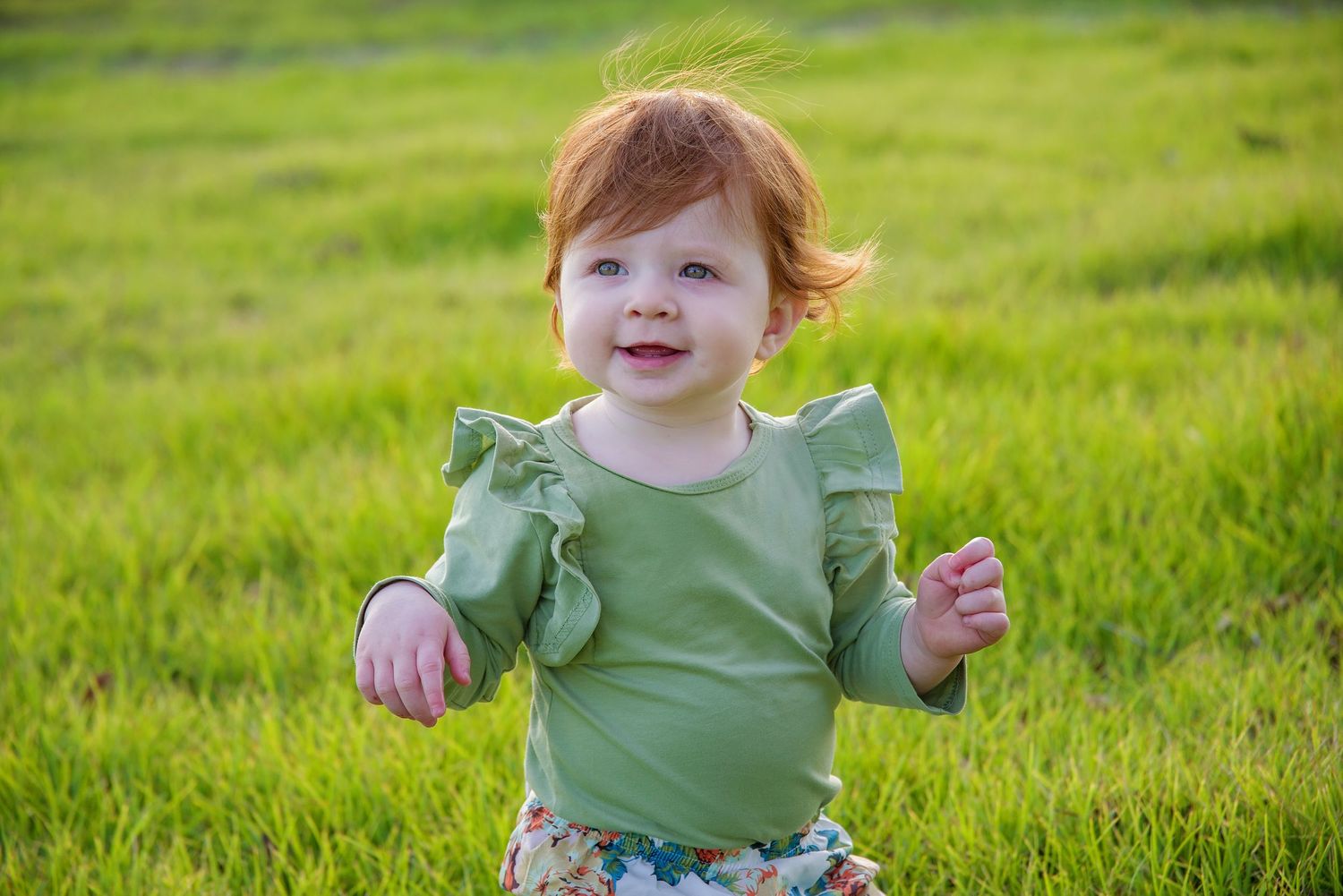 red headed baby sitting in greenery