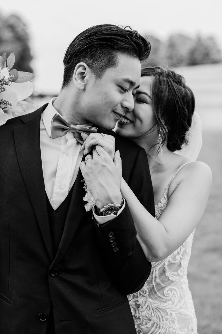 closeup portrait of bride and groom holding hands and touching nose.