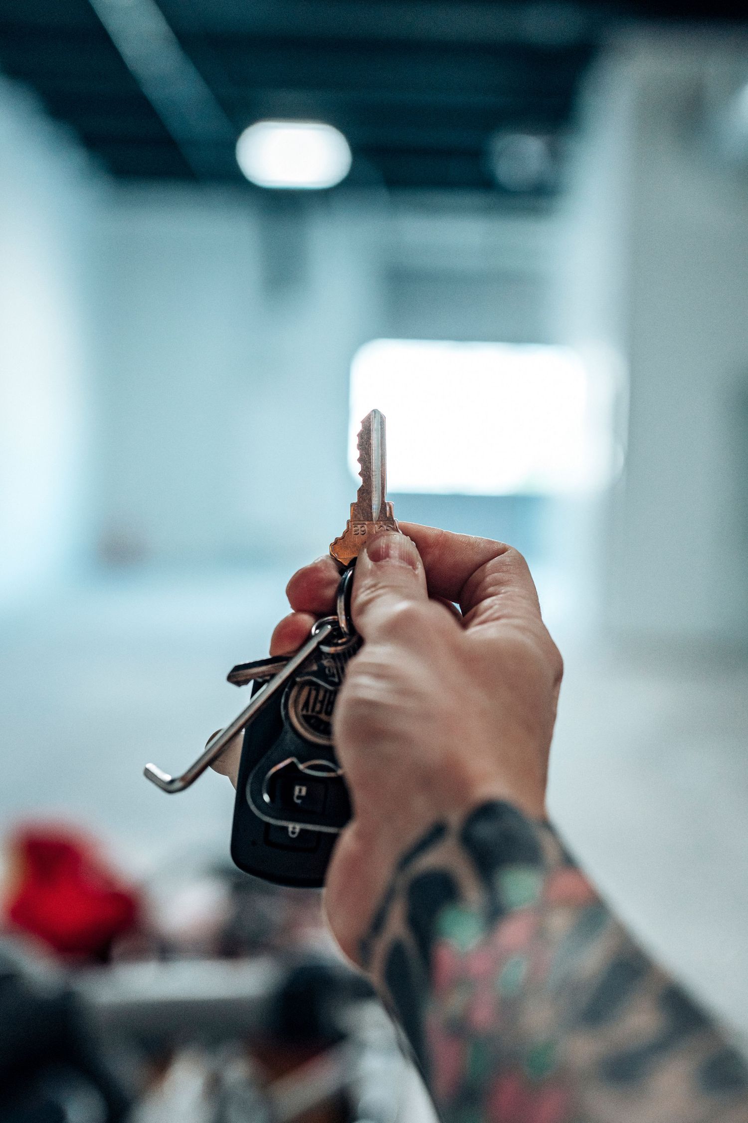 Close-up of tattooed hand holding keys against blurred background.